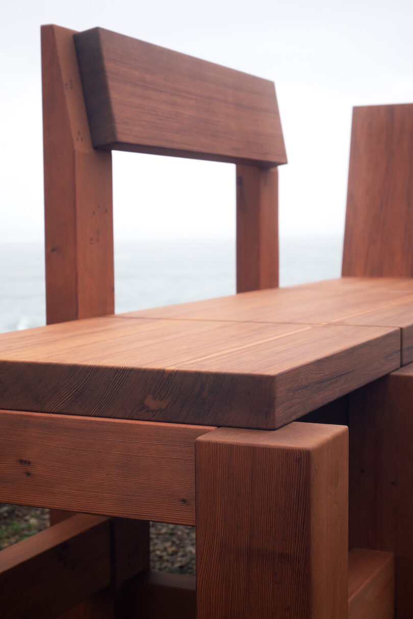 Close-up of a wooden bench with a view of a bench and the sea in the background