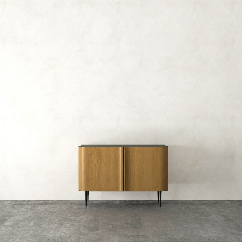 Wooden cabinet with a dark top and two doors, standing against a textured white wall on a gray floor