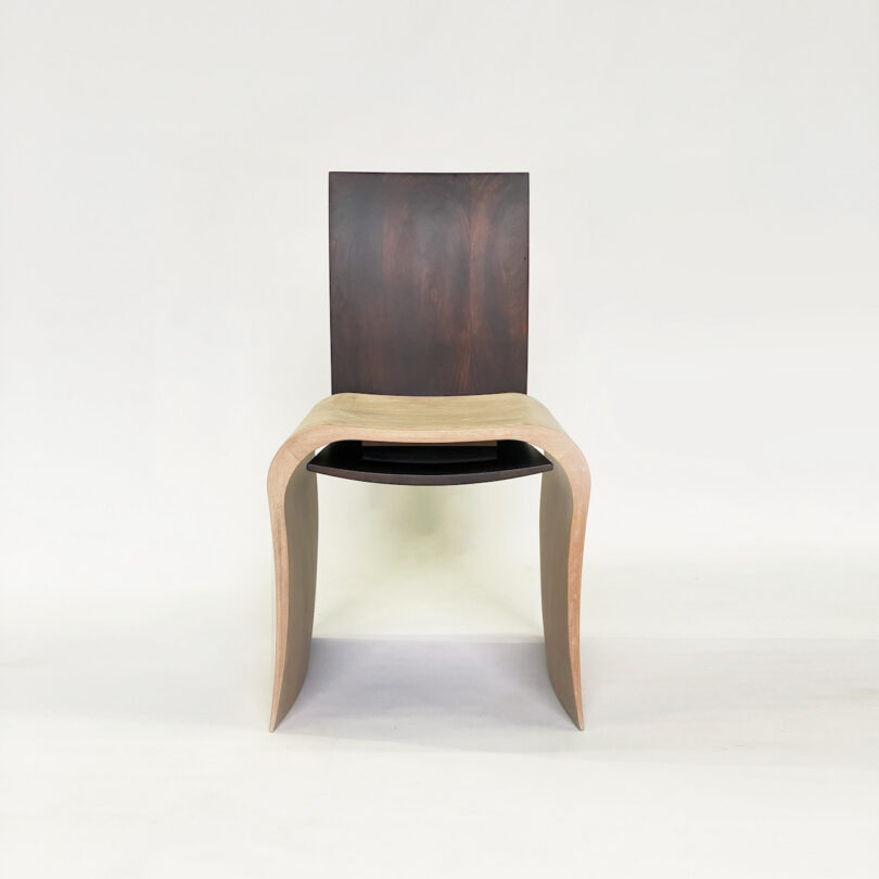 A modern chair with a dark wooden backrest and a light wooden, curved seat, placed against a plain white background