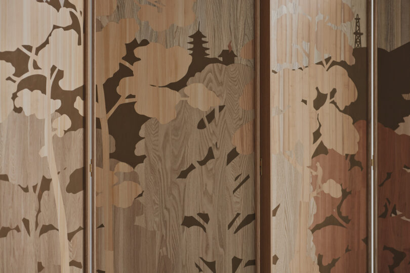 Wooden panels with a nature-inspired design featuring tree silhouettes and outlines of pagodas and towers, in varying shades of brown and beige