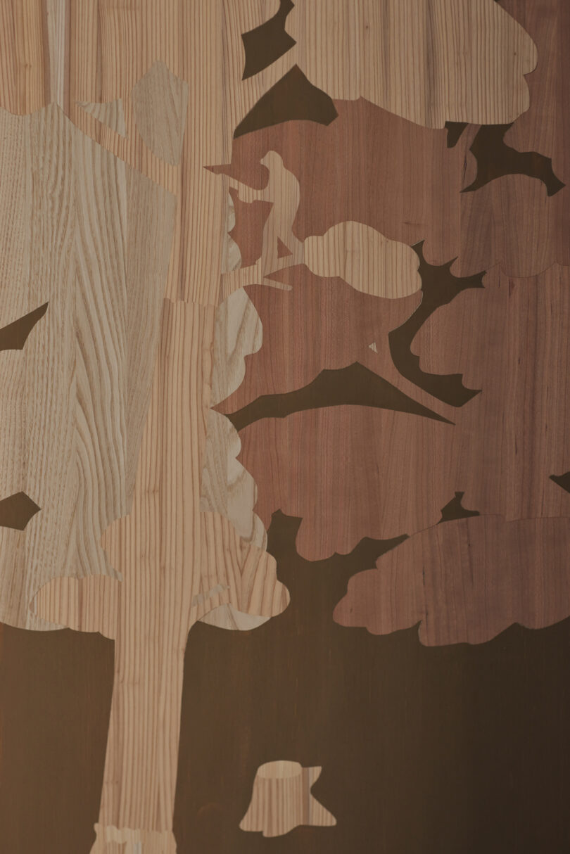 Wooden inlay art depicting a tree with various shades of wood grain against a dark background