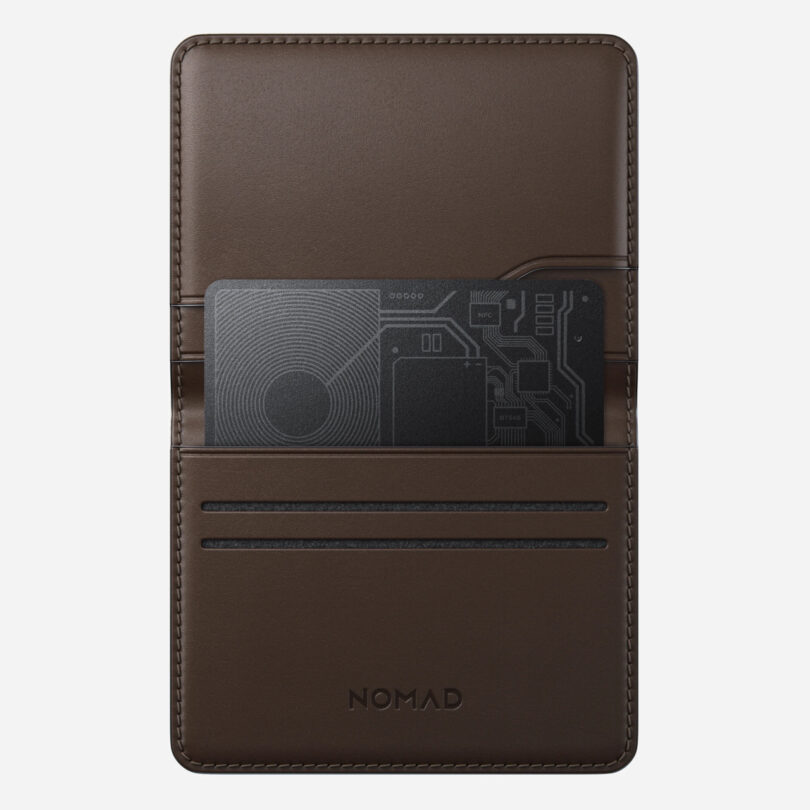 Brown leather wallet with "NOMAD" embossed, holding a black circuit-pattern card in one of the slots.