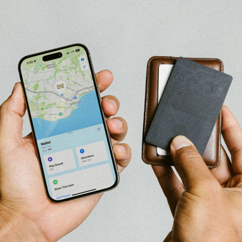 A person holds a smartphone displaying a map and a brown wallet with several cards.