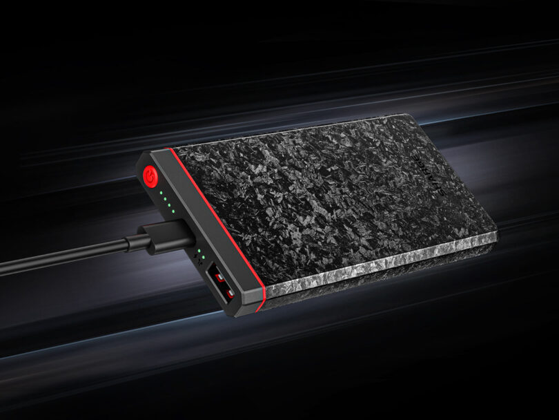 A sleek black power bank with a marbled texture, featuring LED indicators and a charging cable connected.