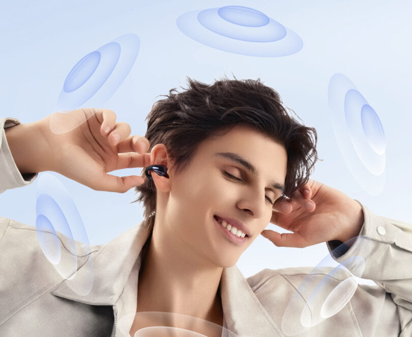 Person smiling with closed eyes, wearing wireless earbuds. Blue sound wave illustrations surround them.