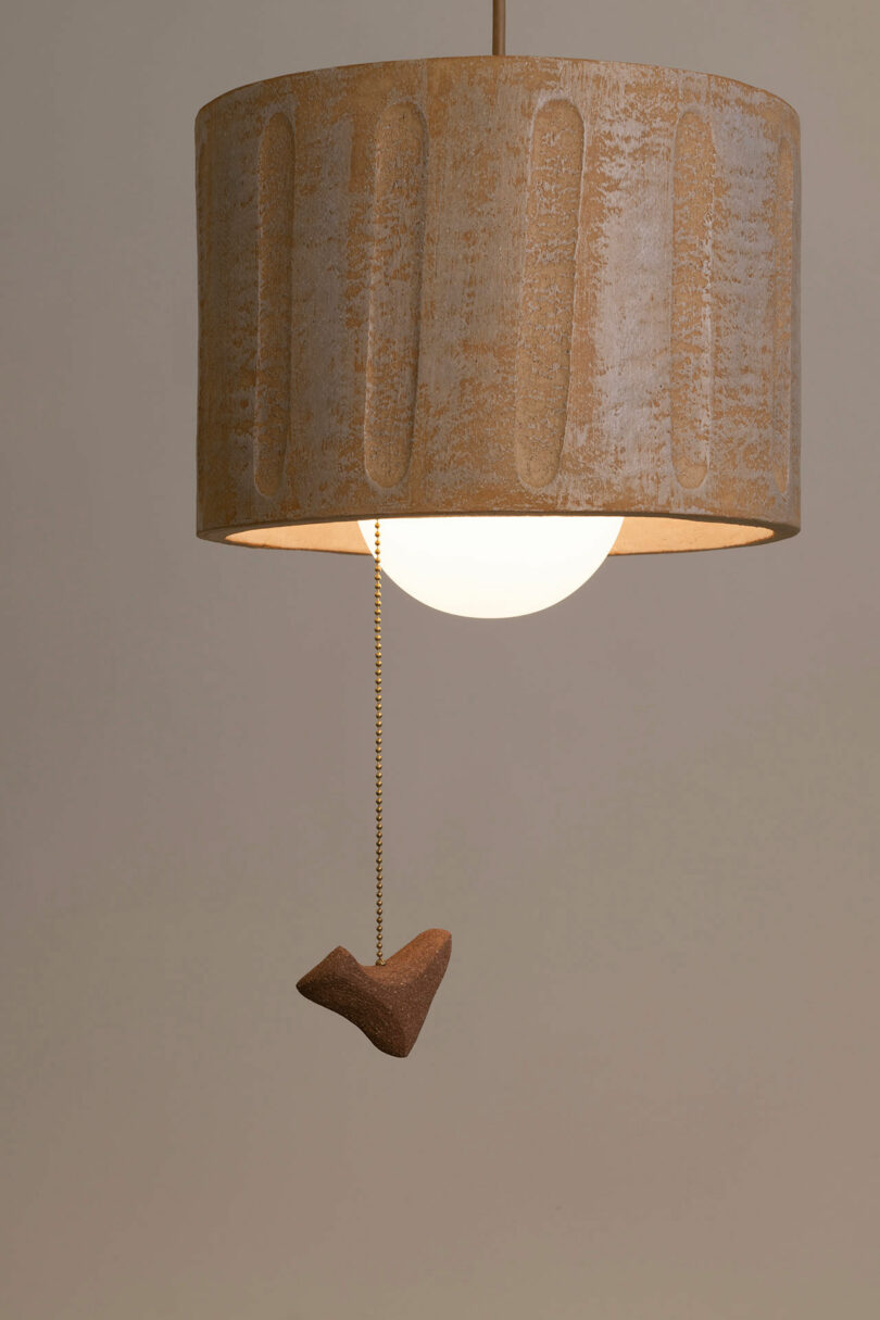 Beige textured lampshade with a pull chain featuring a small, heart-shaped wooden pendant