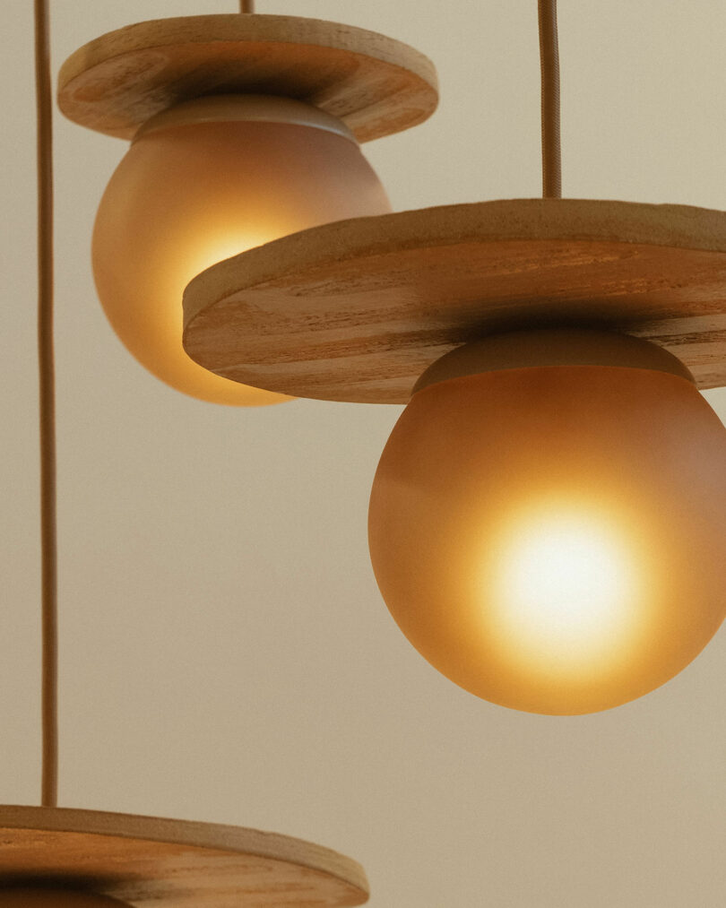 Close-up of round pendant lights with wooden accents, emitting a warm glow