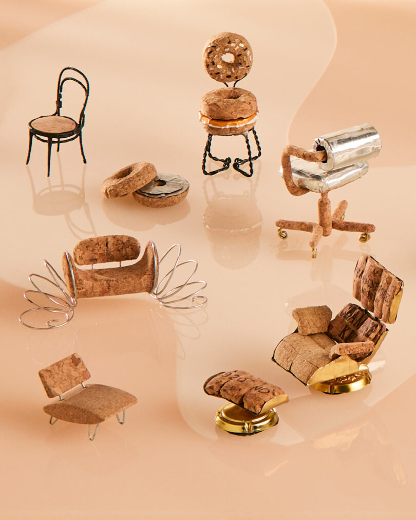 Miniature champagne chairs crafted from cork, wire, and metal are elegantly displayed on a smooth beige surface.