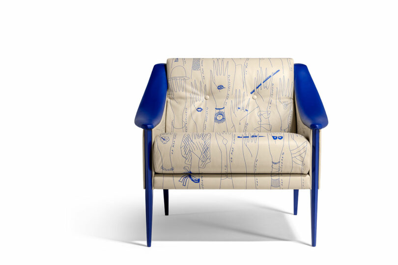 This Gio Ponti-inspired armchair features striking blue arms and legs, while its beige upholstery is adorned with delicate blue line drawings of hands and utensils.