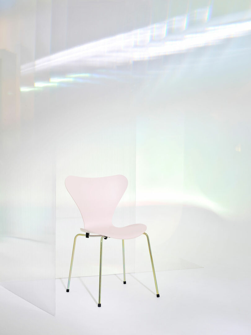 A simple white chair with a curved backrest and metal legs is placed in a minimalist, light-filled room with translucent panels.