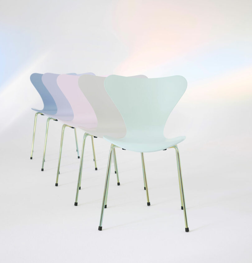 Four pastel-colored chairs in a row on a light background.