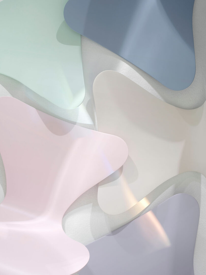 Abstract composition of overlapping, irregularly shaped translucent sheets in pastel shades of pink, blue, green, and white, with soft light reflections.