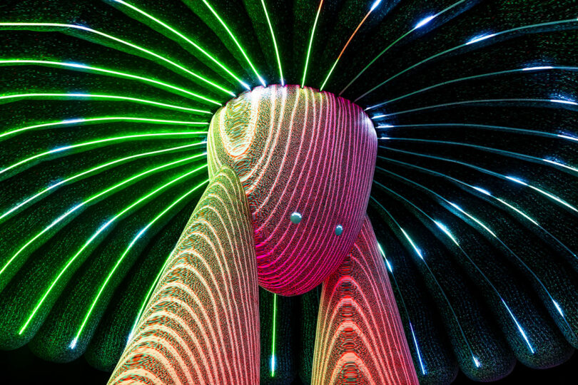 Sculpture de lumière LED abstraite colorée avec des lignes éclatantes vertes et rouges rayonnant vers l'extérieur.