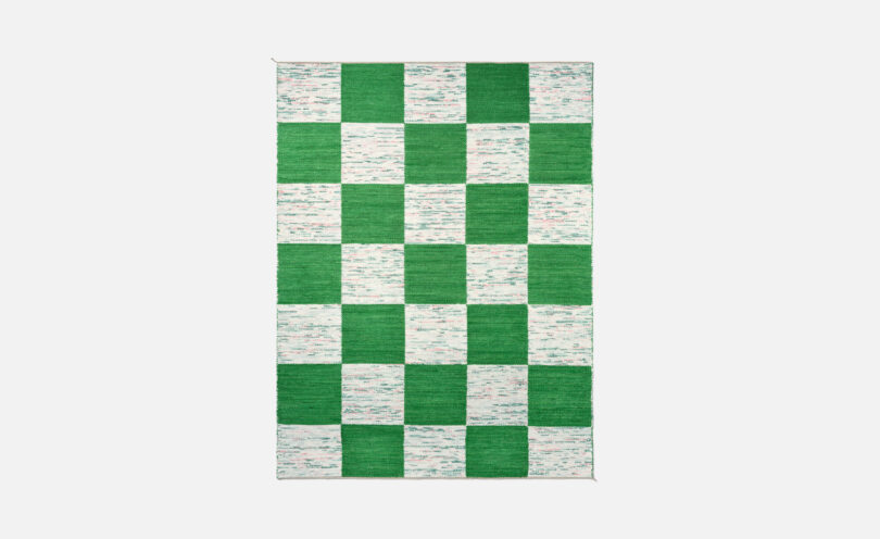 A rectangular rug with a checkered pattern featuring alternating green and white squares.