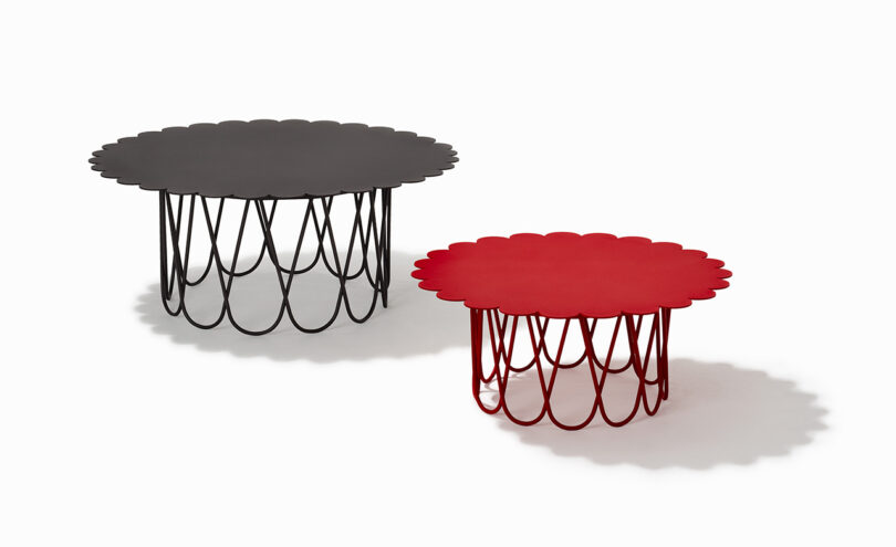 Two round tables with scalloped edges; one black and larger, one red and smaller. Both have open metal bases with a repeating loop pattern.