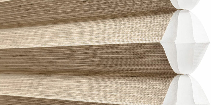 Close-up of a beige pleated cellular shade with a honeycomb structure.