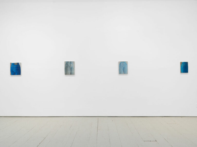 4 small paintings of blue jeans on white gallery wall