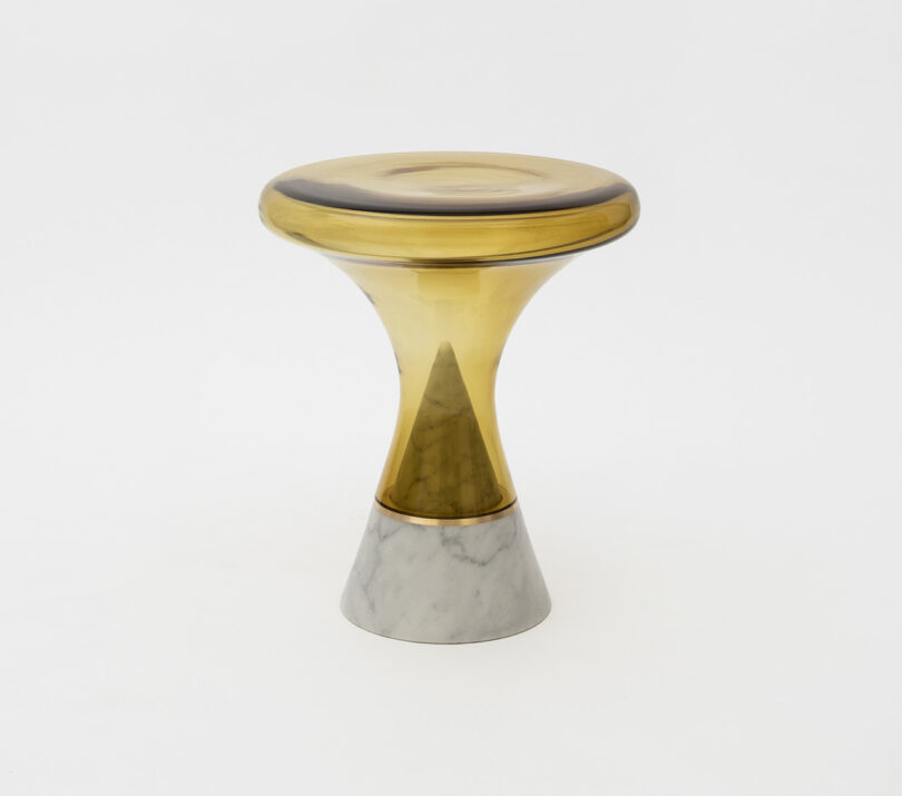 A stool with a round, translucent yellow top and a conical marble base on a plain white background.