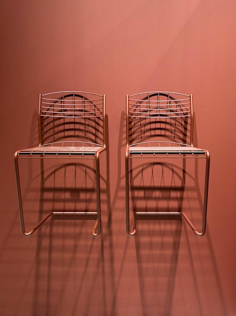 Two wireframe chairs casting shadows against a solid brown wall evoke the minimalist elegance showcased at the Stockholm Furniture Fair.