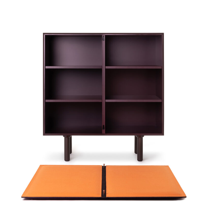 Dark brown rectangular cabinet with four open shelves, standing on two legs. An orange, foldable panel lies on the ground in front.