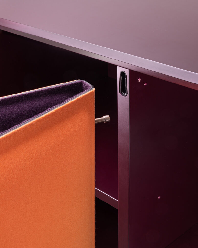 Close-up of a purple and orange modern cabinet, highlighting a pin mechanism securing the door.