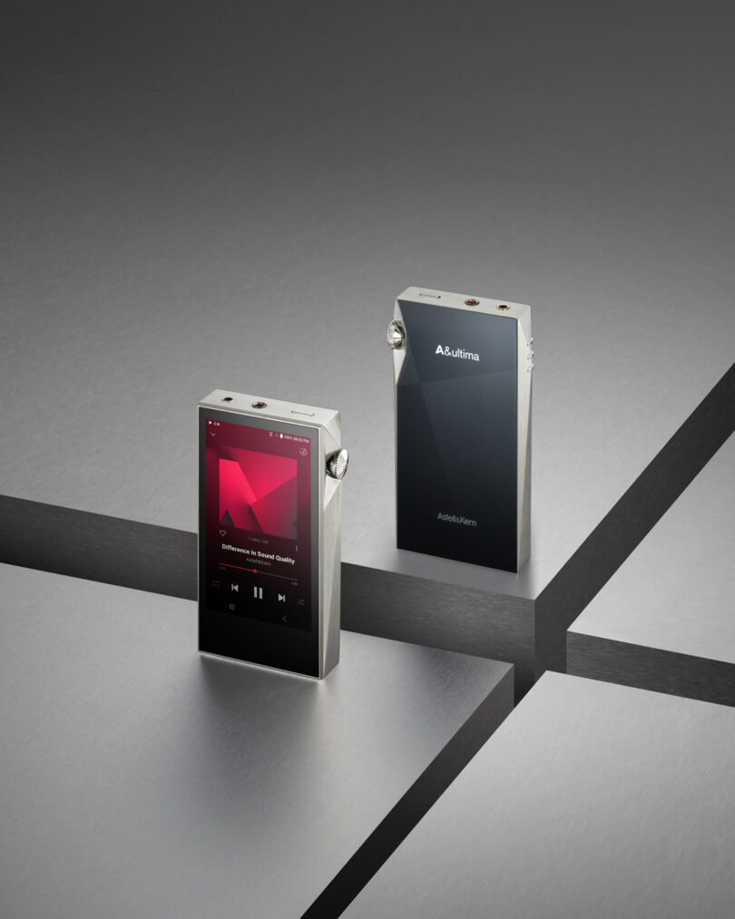 Two portable music players rest on a metallic surface, one showing a screen with music controls, while the SP3000M highlights its sleek logo.