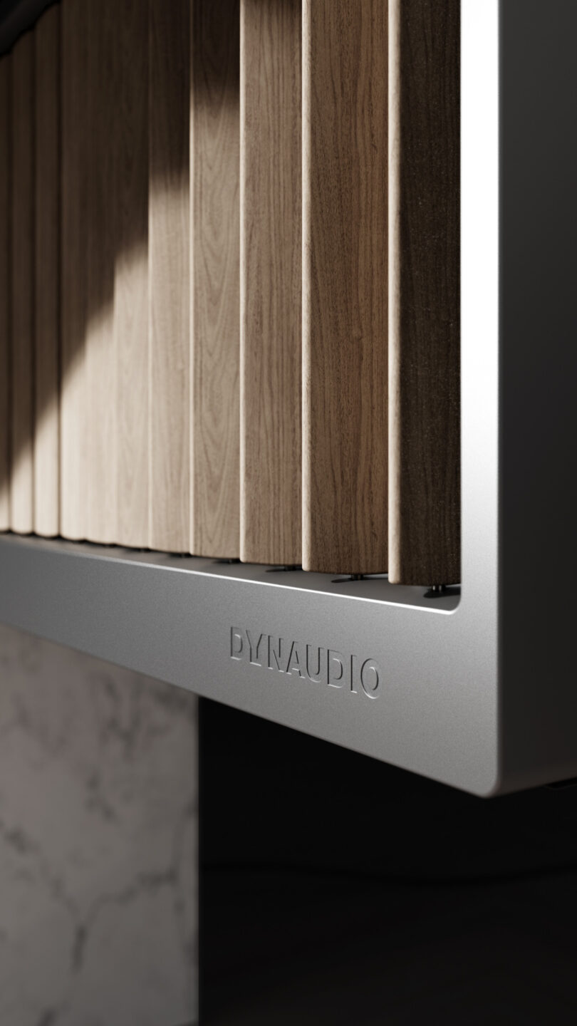 Close-up of a Dynaudio speaker with a sleek, modern design featuring vertical wooden slats and a metal base.