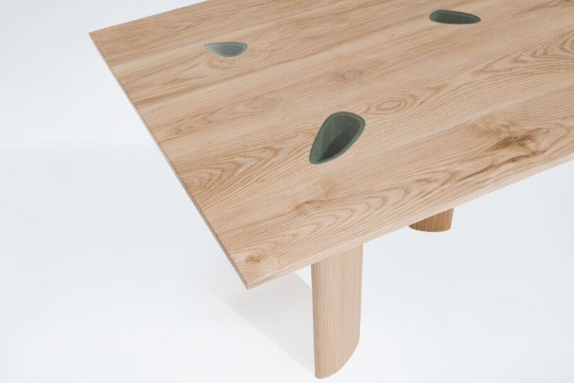 A wooden table with a smooth finish, featuring three leaf-shaped green inlays