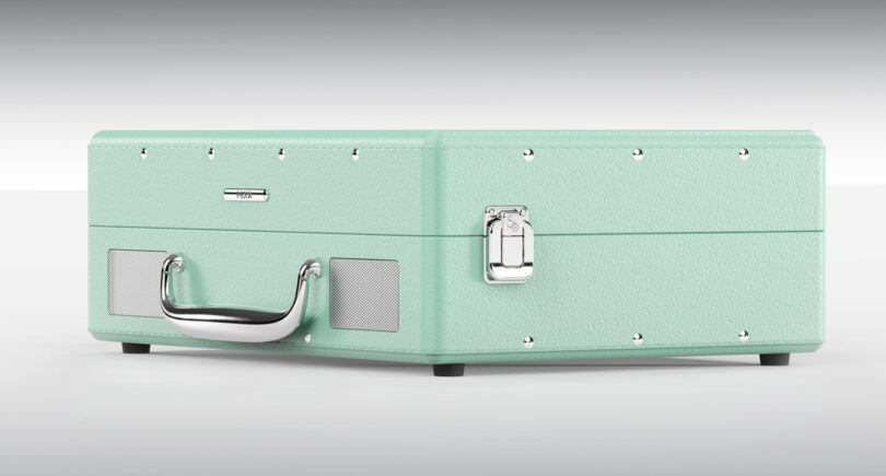 A closed, mint-green textured carry case with silver hardware, including a latch and a handle. The case is positioned on a light surface.