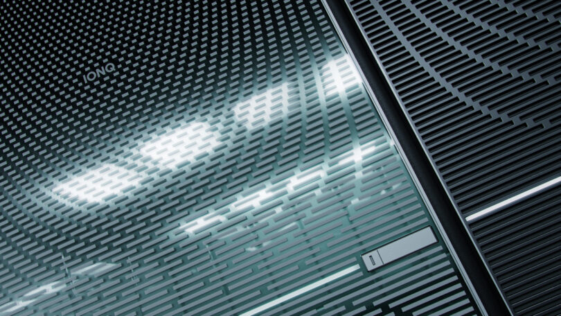 Close-up of a metallic, textured quantum computer labeled "IONQ." The surface features a pattern of lines and a small section with a label marked "1.