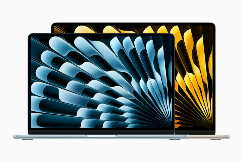 Two laptops sit side by side, showcasing abstract geometric patterns on their screens; the left MacBook Air displays calming blue tones, while the right screen bursts with vibrant yellow hues.