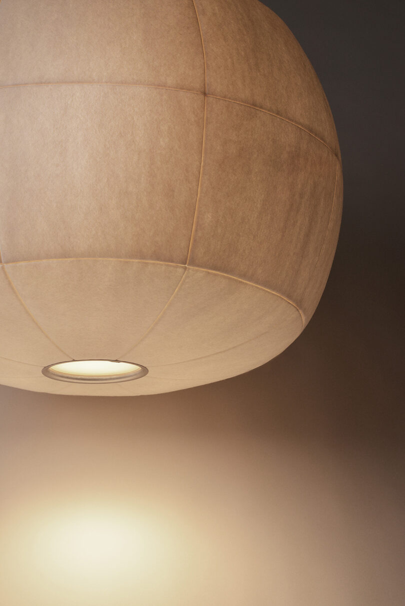 A round, beige ceiling lamp with a textured surface illuminates part of the ceiling, casting a warm glow downward.