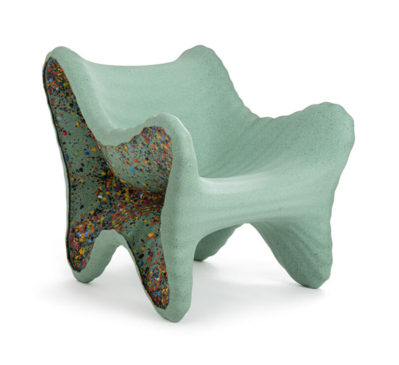 A sculptural, light green armchair inspired by In-Side Thomas Heatherwick, featuring thick, curved sides and multicolored speckled interior surfaces.