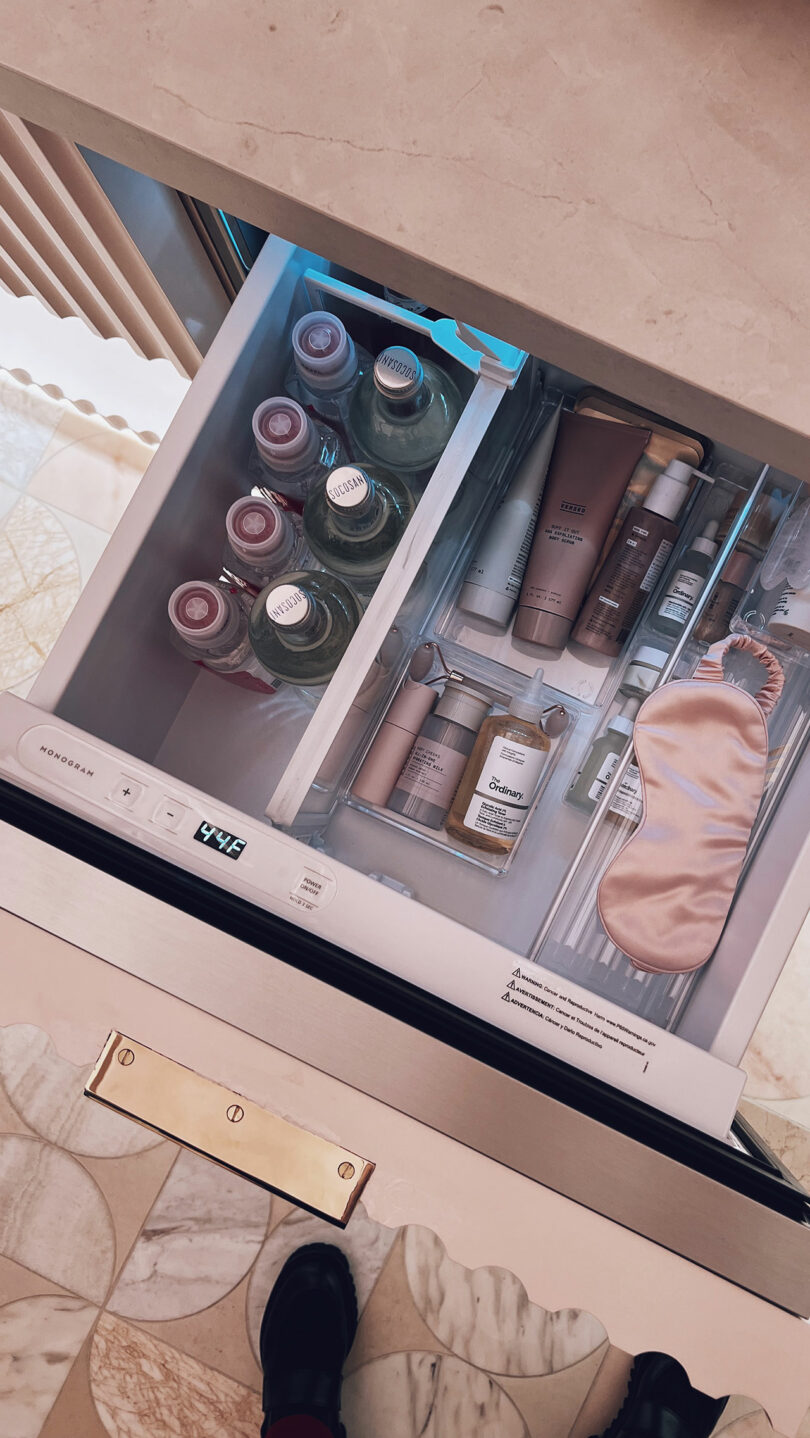 A drawer with neatly organized skincare products, KBIS essentials, bottled drinks, and a pink sleep mask.