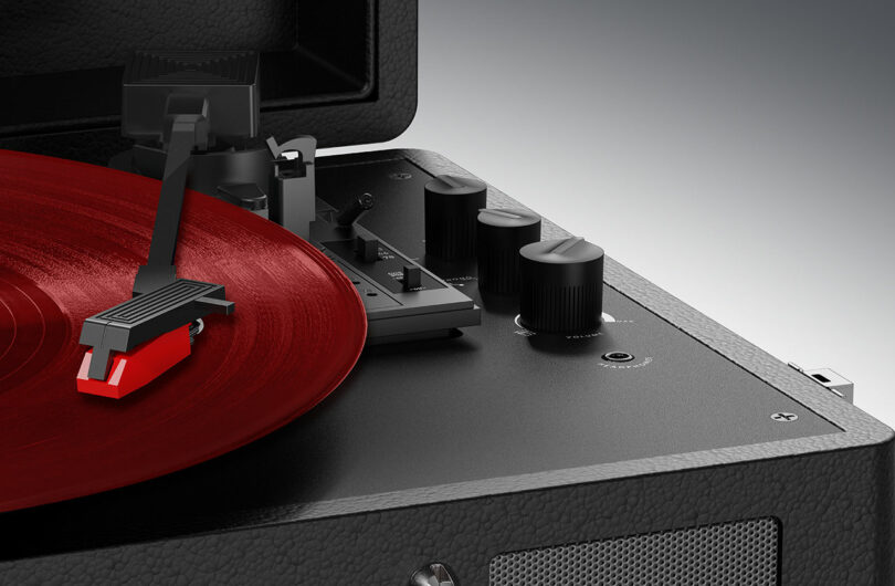 Close-up of a Mixx turntable playing a red vinyl record. The image showcases the tonearm, stylus, and control knobs on a sleek black textured surface.