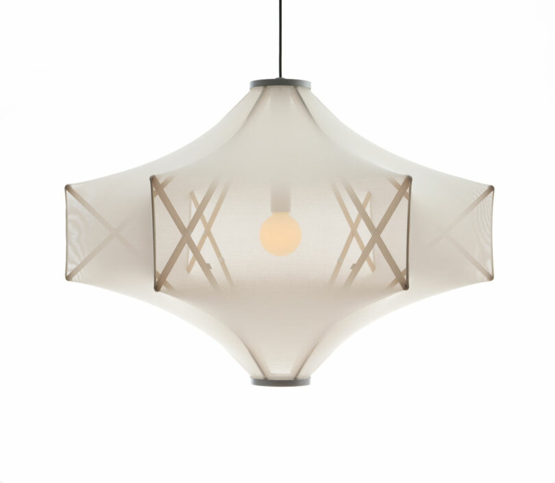 Discover the Sorpresa pendant light, crafted by Samuel Wilkinson. It boasts a modern translucent fabric shade with an angular, geometric design that encases a soft, glowing bulb inside.