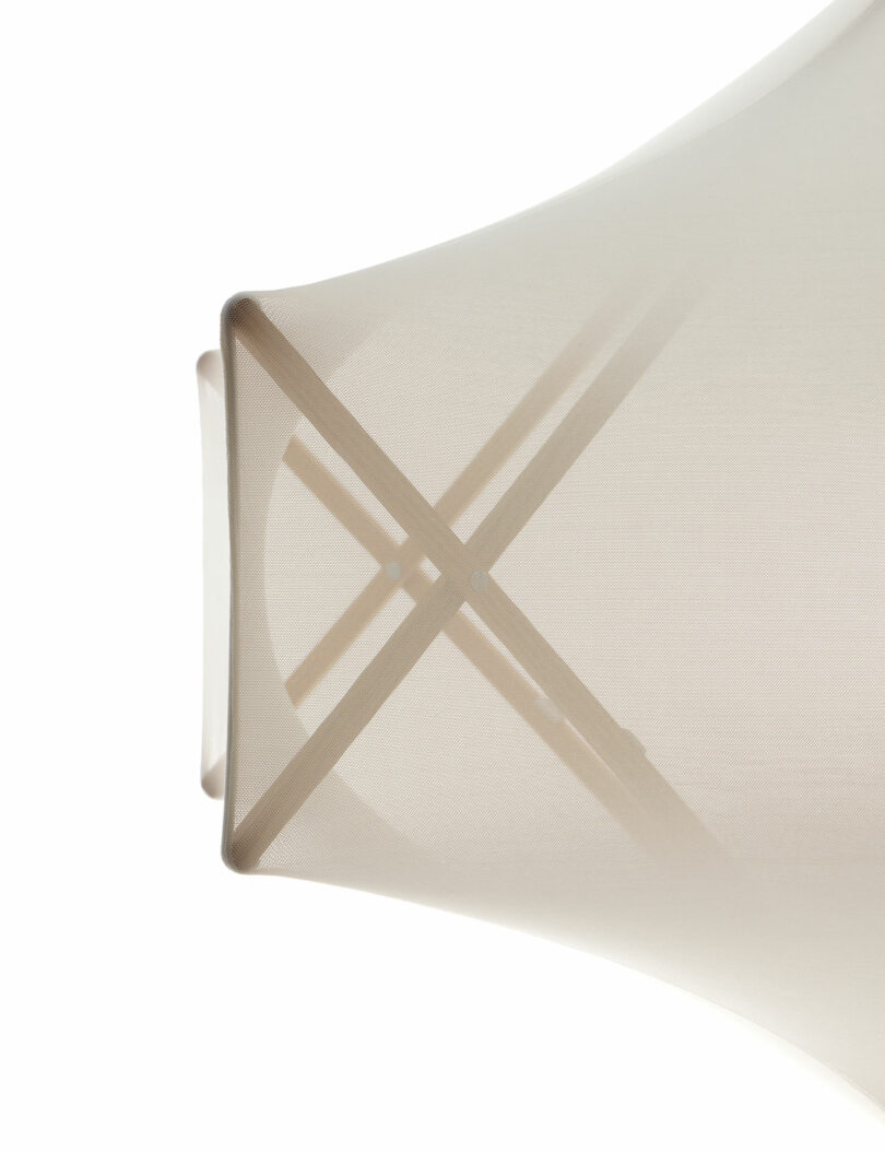 Close-up of a translucent fabric, its geometric pattern elegantly revealing interplay of light and shadow, reminiscent of Samuel Wilkinson’s minimalist design surprises.