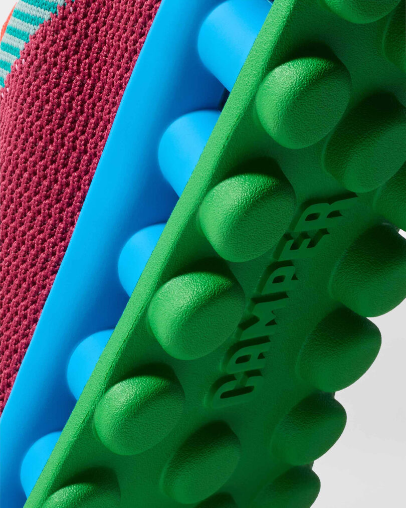 Close-up of a shoe's colorful sole with bold green round grips and the word 