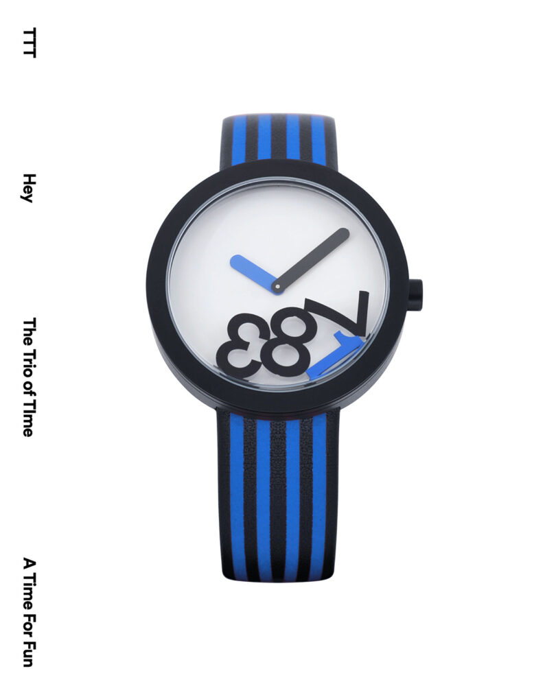 A wristwatch with a white face, black case, and blue-and-black striped band. The numbers 6, 7, 8, and 9 are visible, arranged non-traditionally. Black and blue hands indicate time.