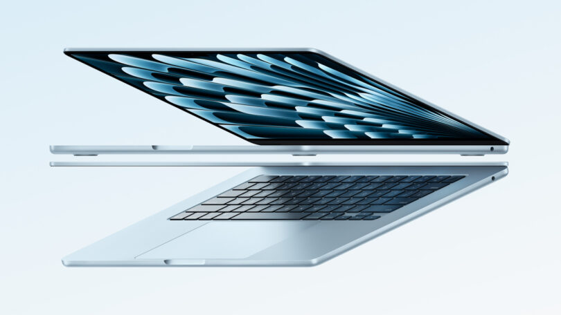 Two sleek laptops are aligned back-to-back, showcasing an open, seamless display and keyboard. The devices appear modern and thin, set against a light blue background.