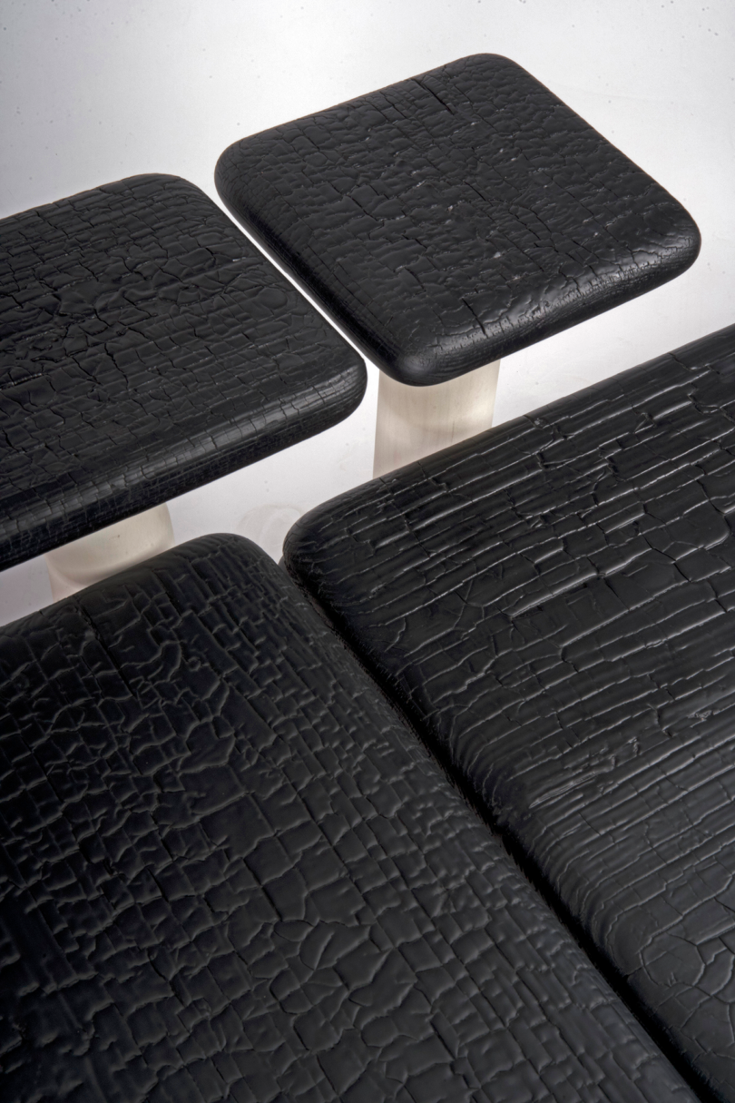 Square black tables with a textured, cracked surface and sleek metal legs are arranged closely together