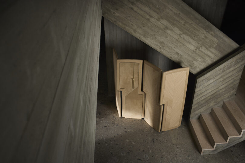 Wooden folding partition placed beside concrete staircase and walls in dim lighting