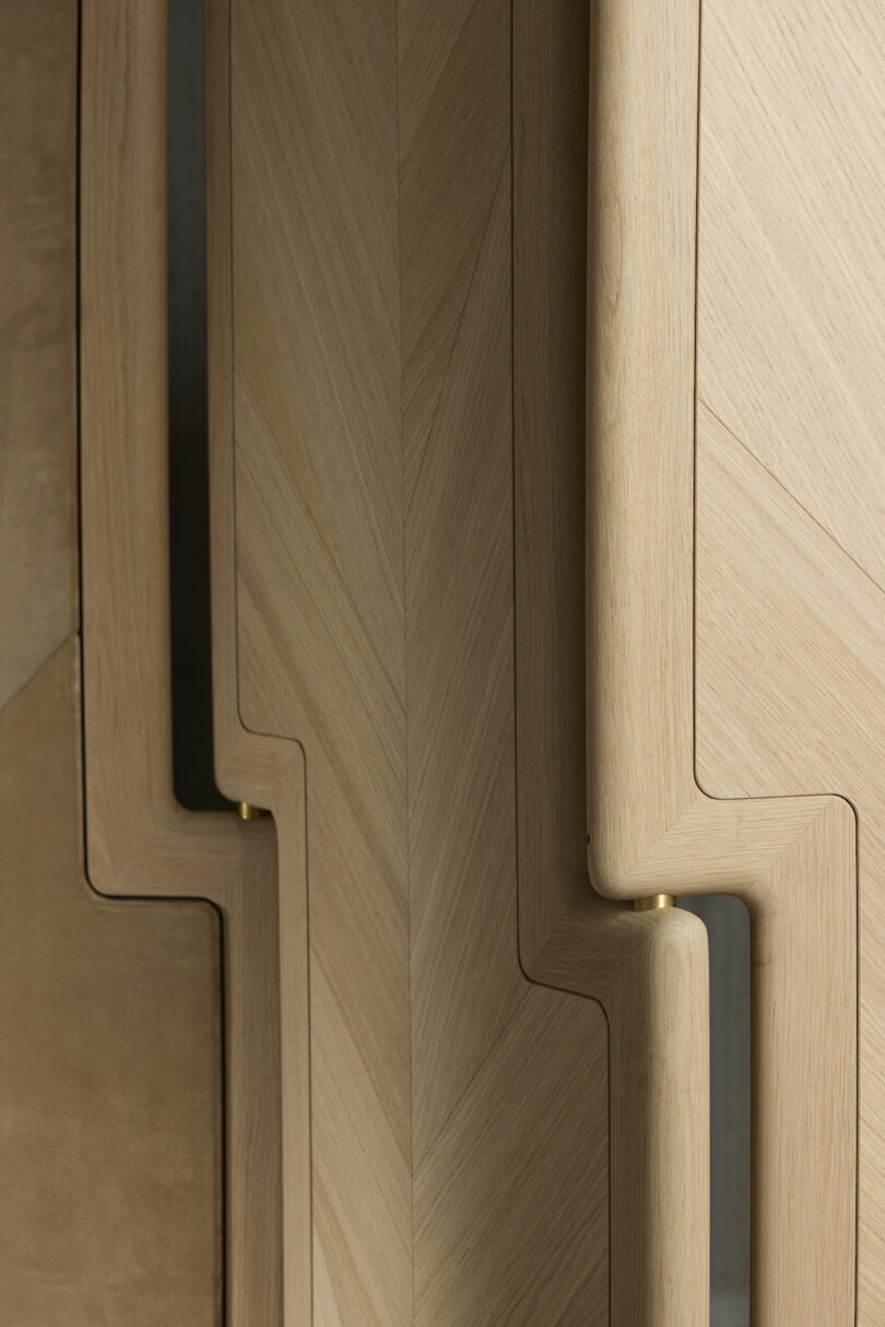 Close-up of beige wooden panels with a zigzag pattern and curved edges, featuring a chevron design in a vertical alignment
