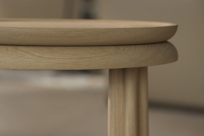 Close-up of a round wooden table with a smooth surface and cylindrical legs, showing the natural wood grain and texture