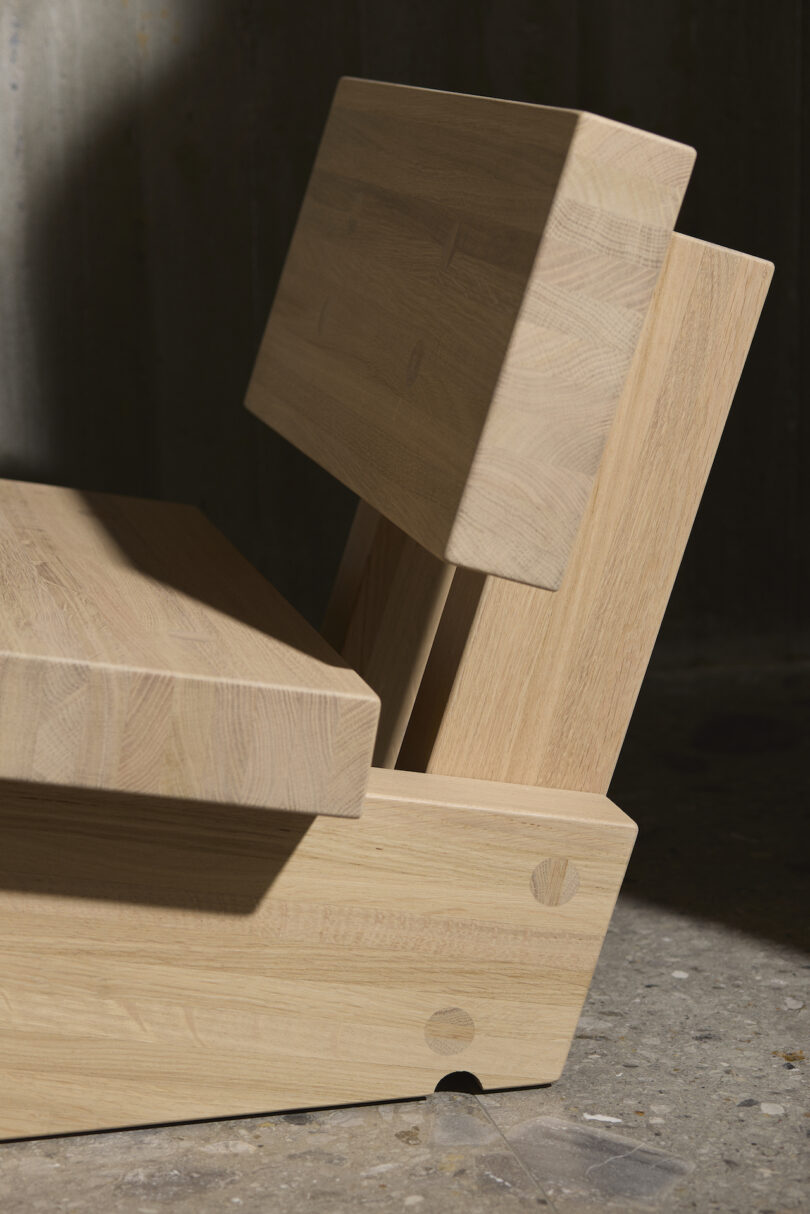 Wooden chair with a minimalist design, featuring flat seat and backrest panels, angled joints, and visible wood grain