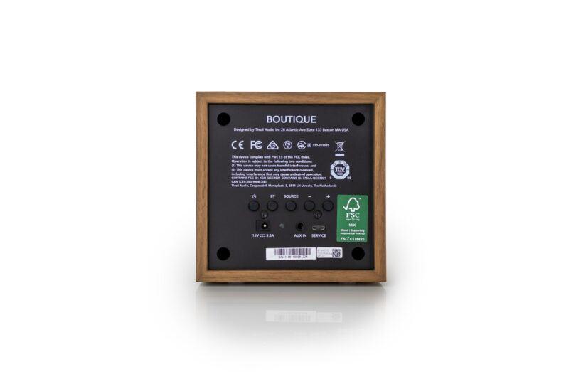 Back view of a wooden square electronic device, reminiscent of a Tivoli design, showcasing multiple ports, buttons, and labels, including the brand name “Boutique” and various certification marks.
