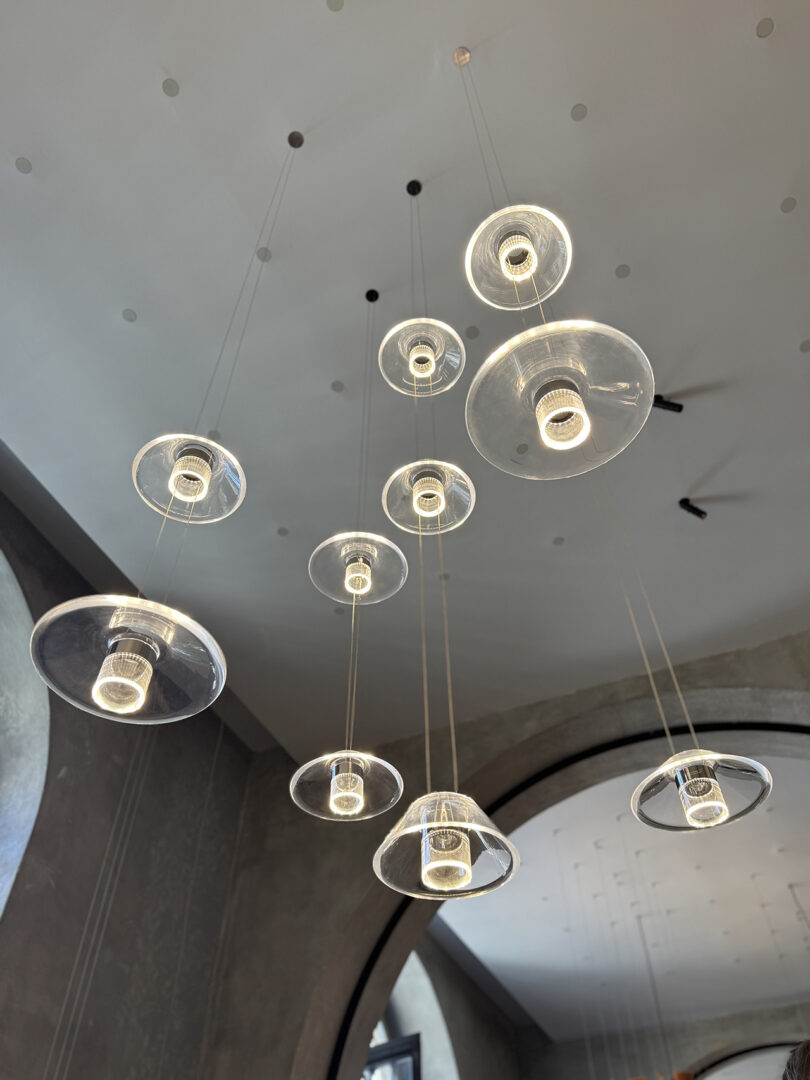 A cluster of modern Aura pendant lights by Snøhetta with clear glass shades hangs from the ceiling in a contemporary interior space.