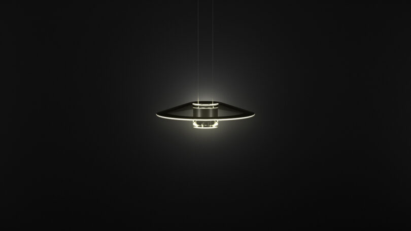 A modern, circular Aura Snøhetta pendant light fixture hangs from the ceiling, emitting a soft white glow against a dark background.