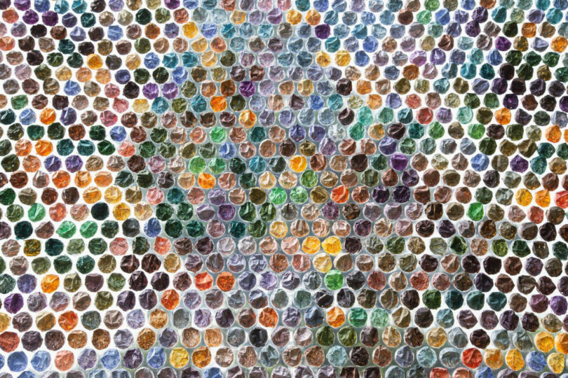 A mosaic pattern composed of small, hexagonal tiles in various colors, arranged closely together to form an abstract, symmetrical design reminiscent of Katherine Duclos’s vibrant artistic style.