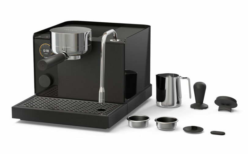 A black Fellow espresso machine with a steam wand is shown alongside accessories including a milk frothing pitcher, tamper, filter baskets, and portafilter parts on a white background.